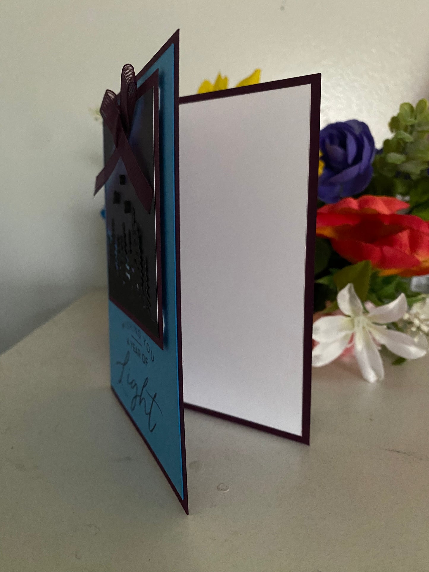 Open card with blue interior and white exterior, featuring a bow, on a surface with northern lights in the background.